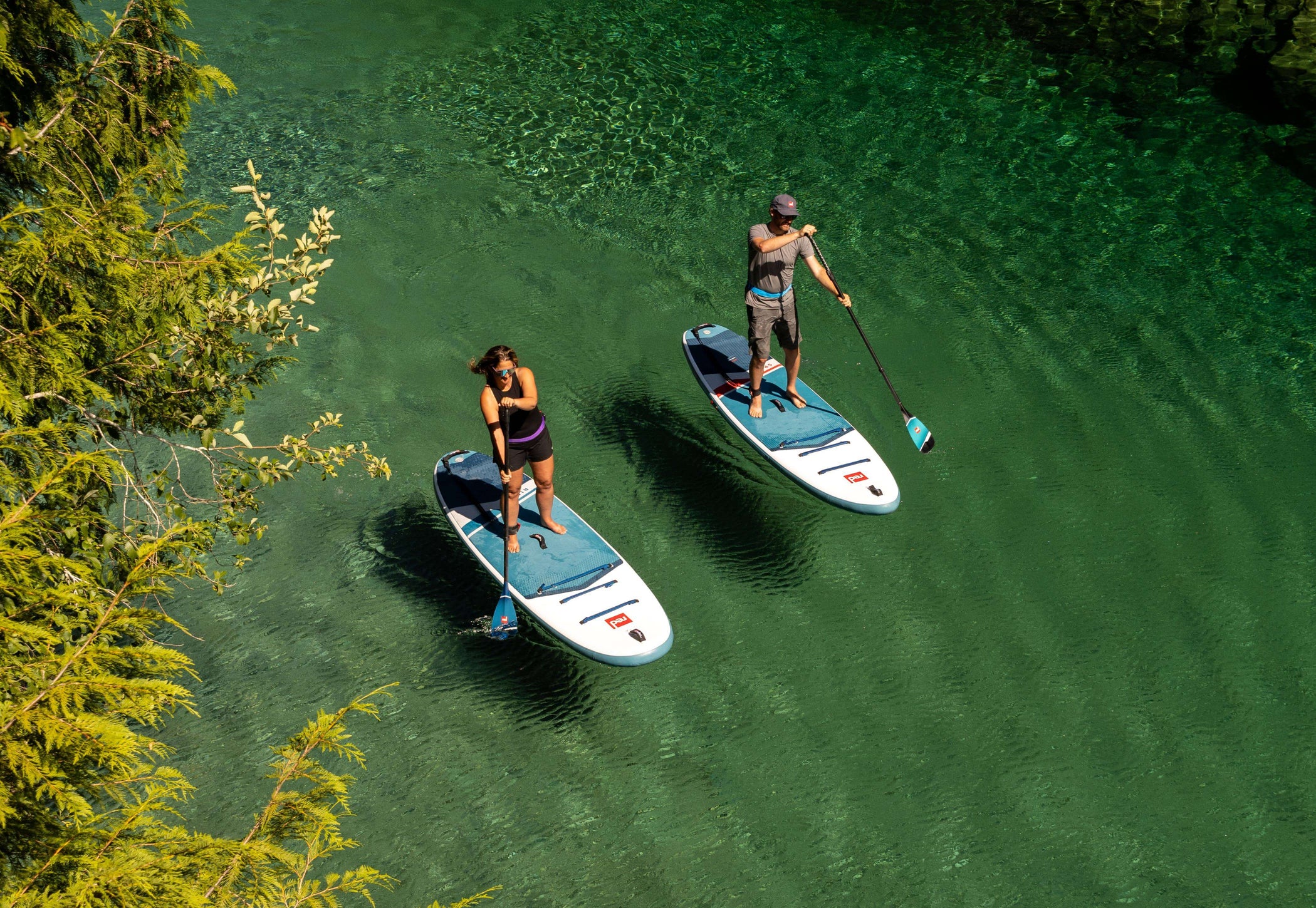 aerial image of two people on red paddle co sup boards