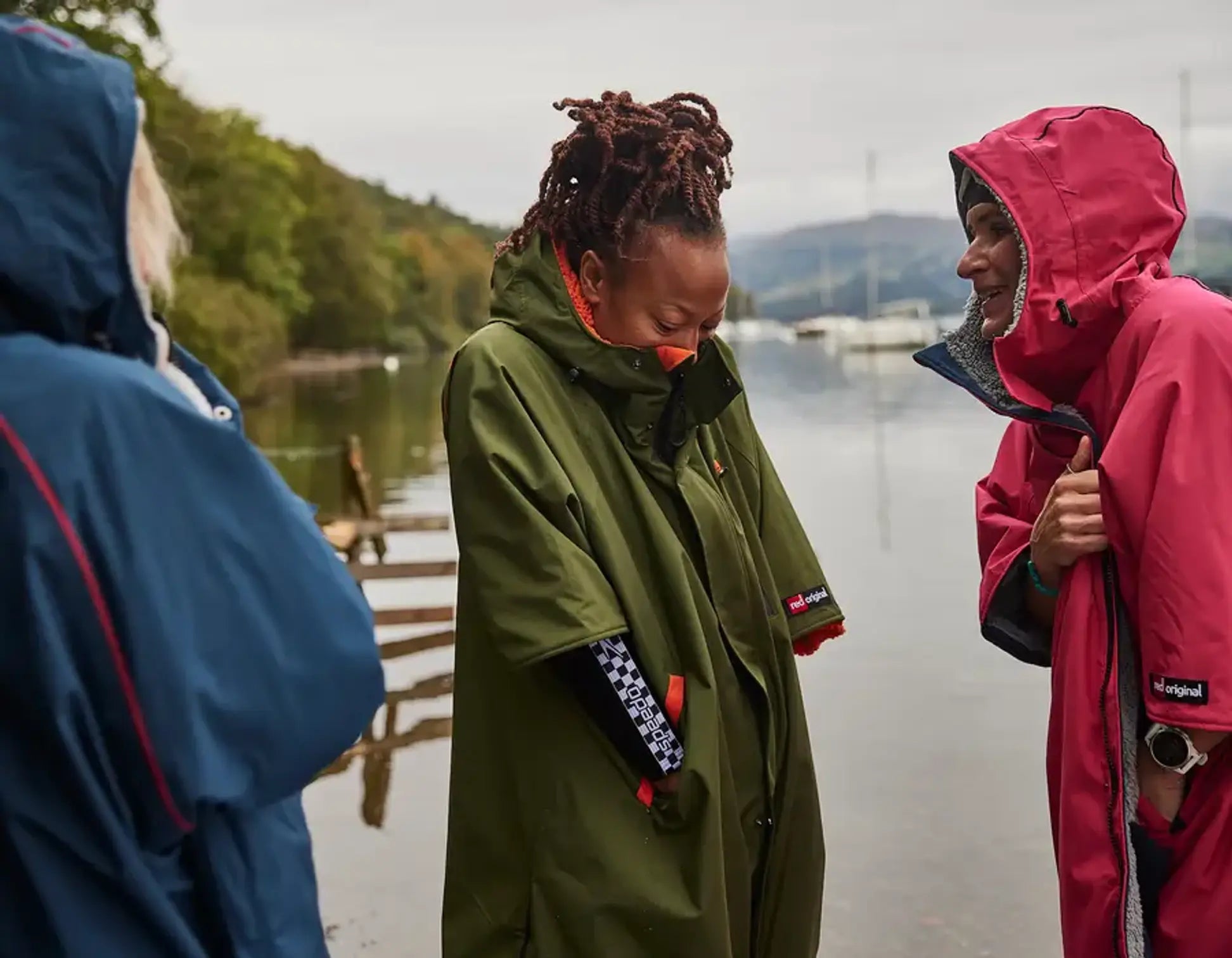 3 people wearing the changing robe, talking beside a lake