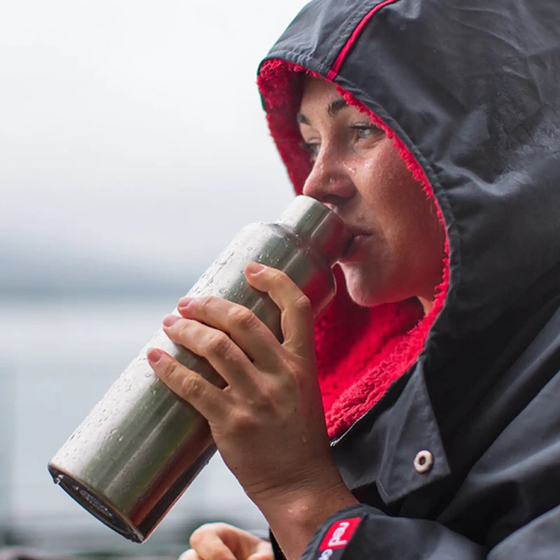 A close up of a woman drinking from a insulated bottle