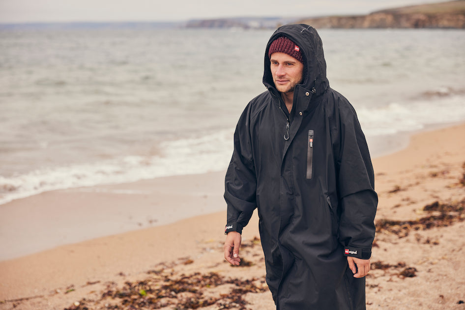 Man walking on the beach wearing Red Original Merino Beanie and Pro Change Robe