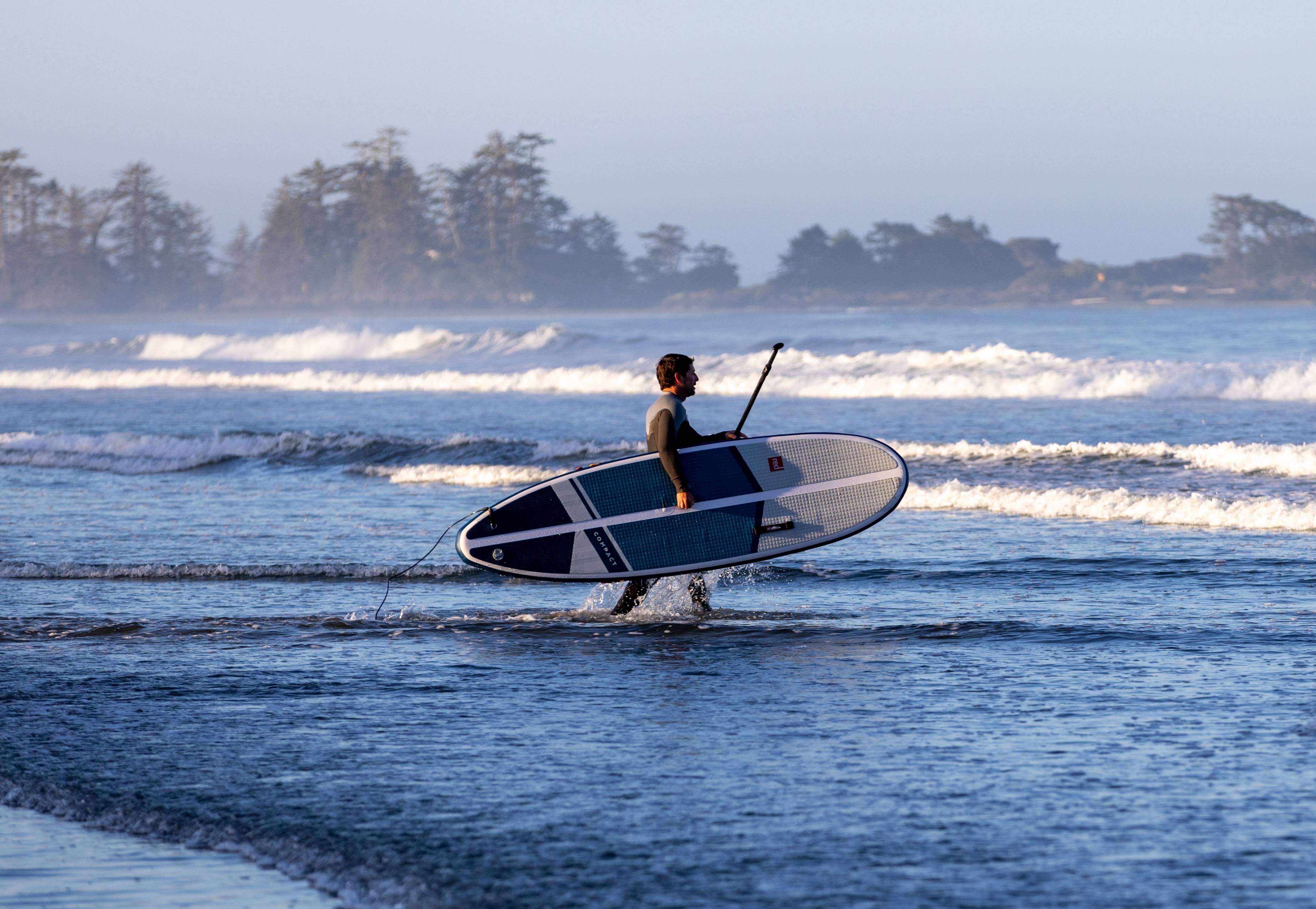 man entering the sea with inflatable paddleboard