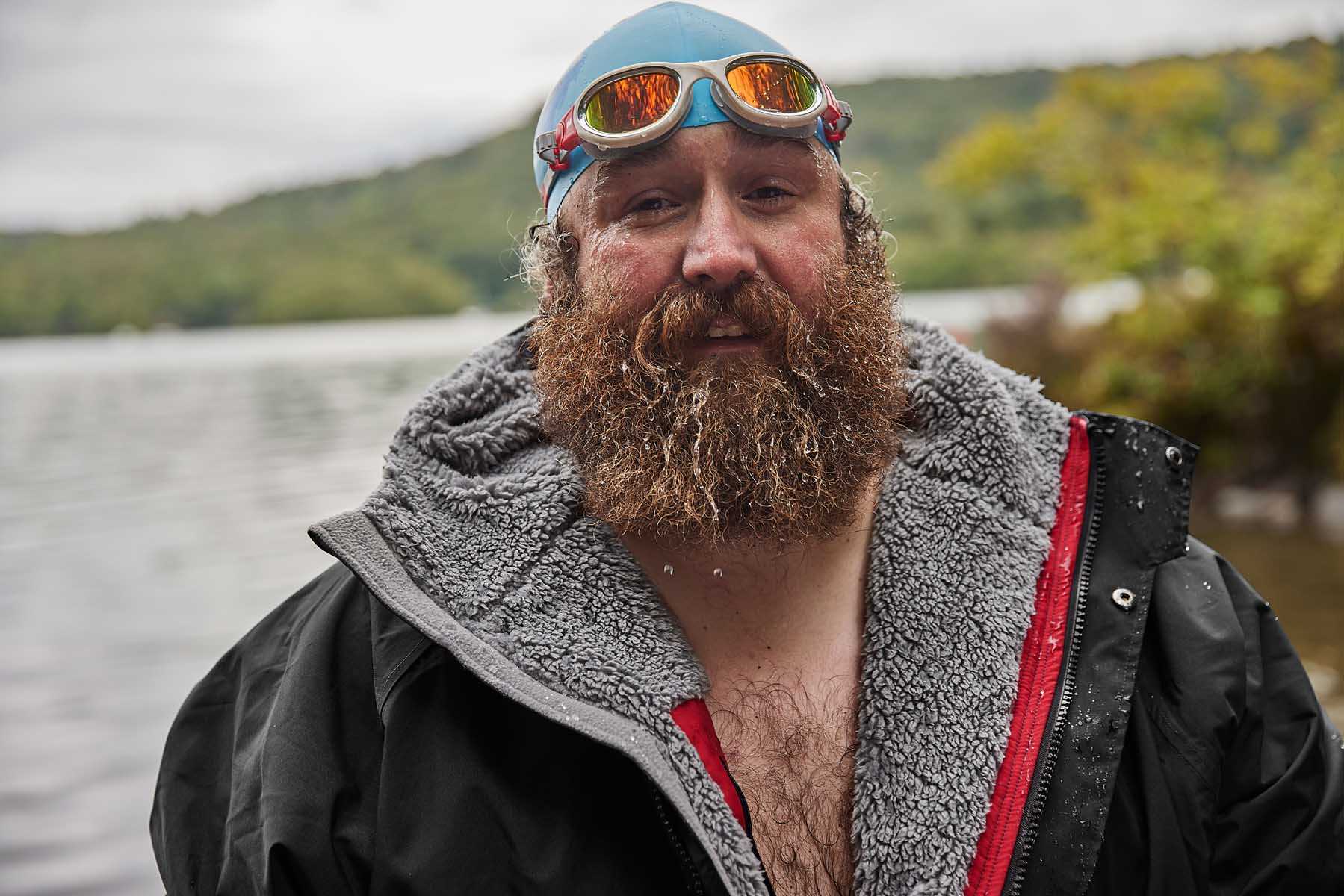 bearded man wearing swim cap, goggles and waterproof changing robe