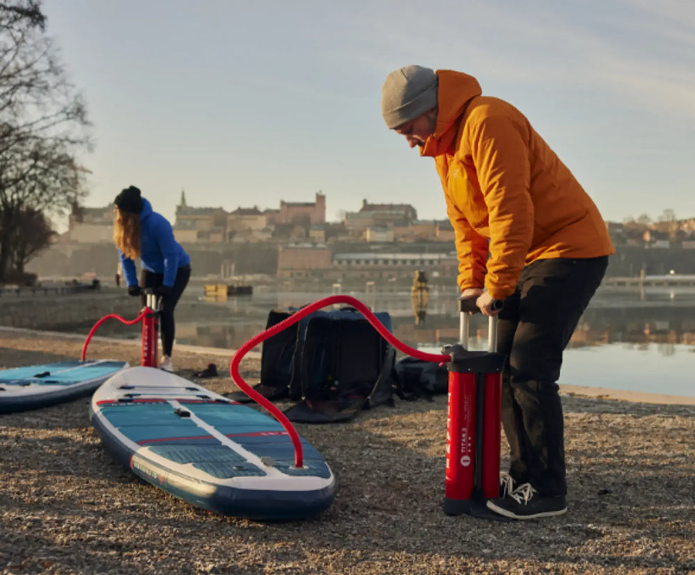 person putting air into inflatable paddle board
