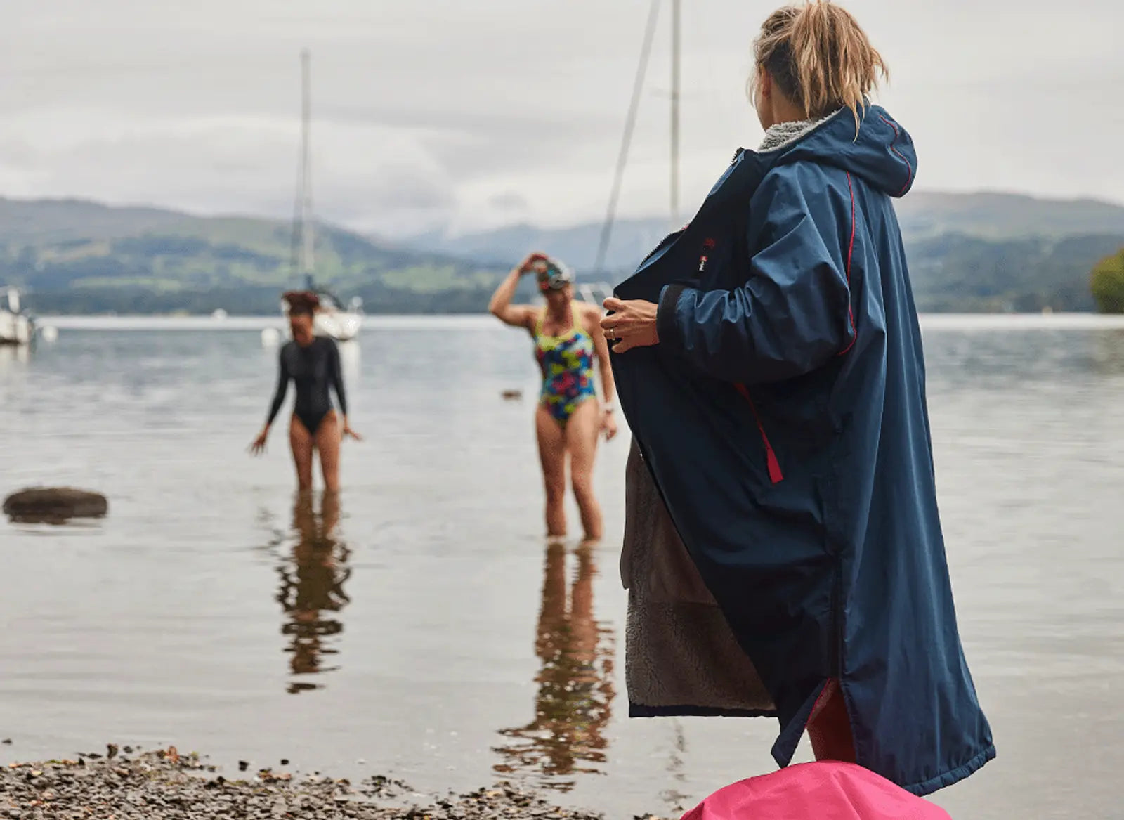 A woman wearing her Red Pro Change Robe and 2 other women paddling in the sea