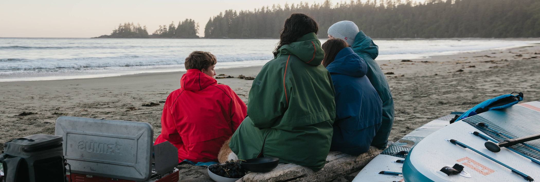 a family sat on the beach wearing red changing robes