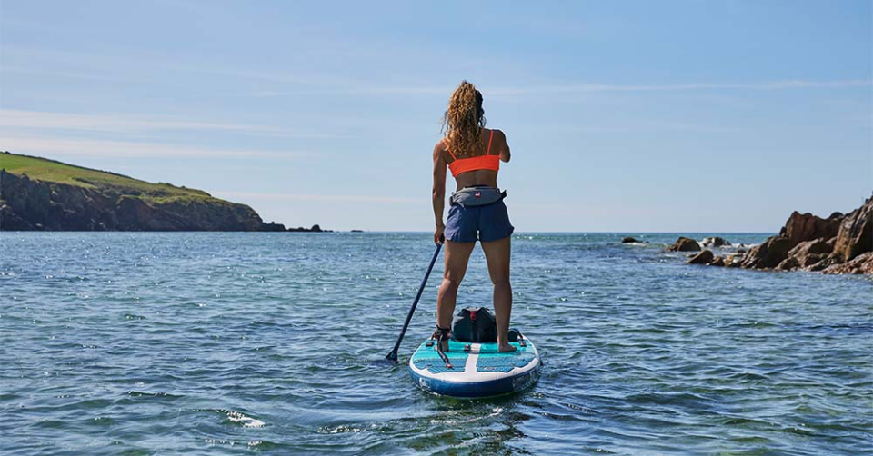 Woman paddle boarding wearing Red Original personal floatation device