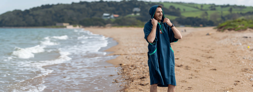 A man wearing his Red Quick Change Robe on the beach