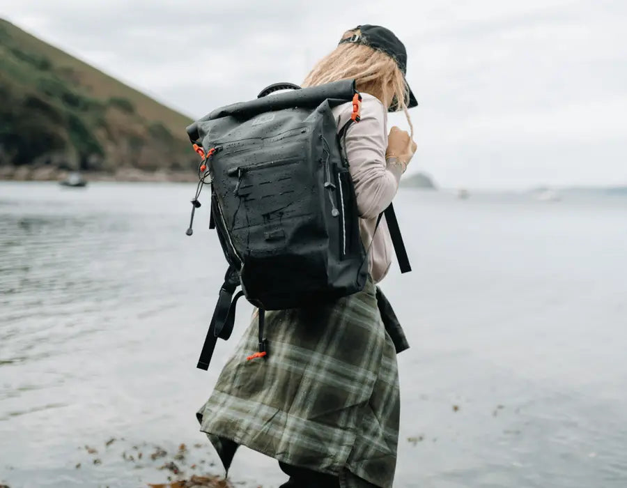 A woman carrying her Red adventure backpack on the beach