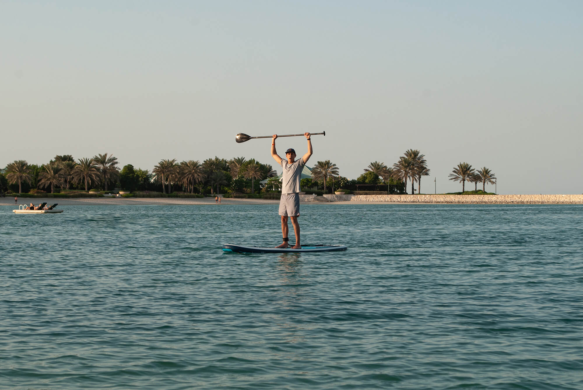 Paddle Boarder In Bahrain With His Paddle Help Over His Head