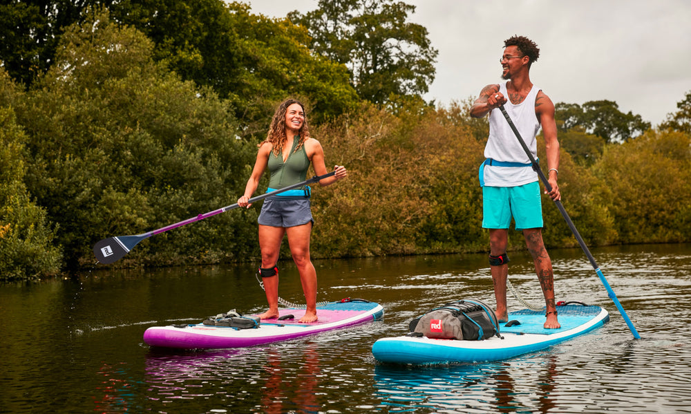 man and woman on red paddle boards