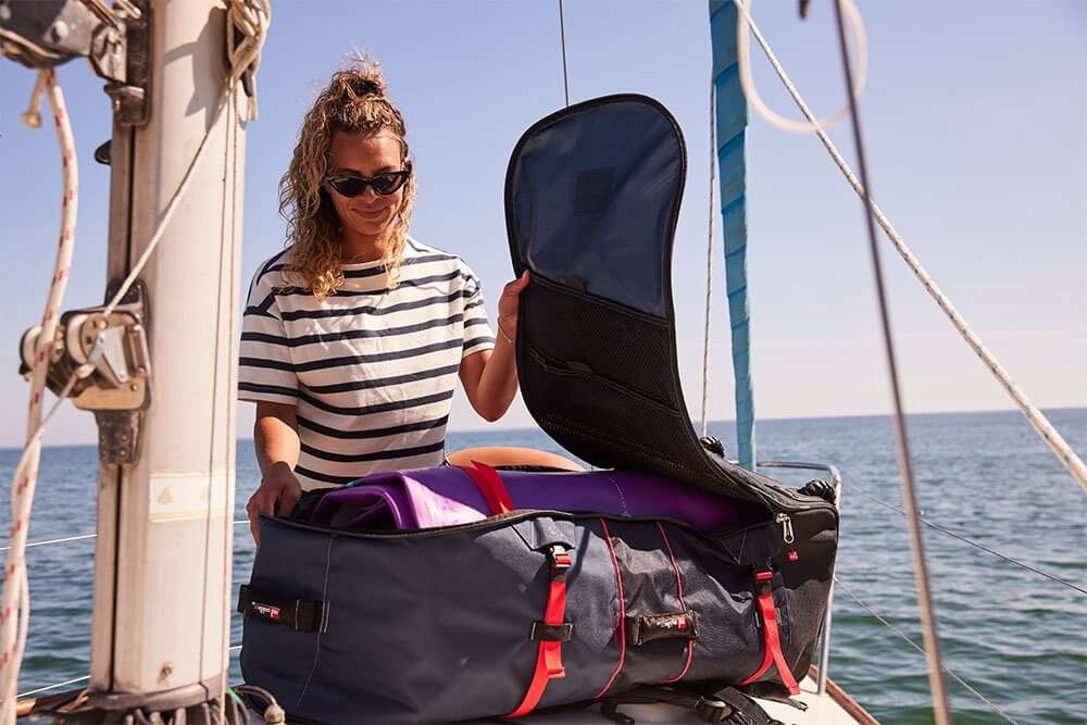 woman storing paddle board in paddle board bag on a boat deck