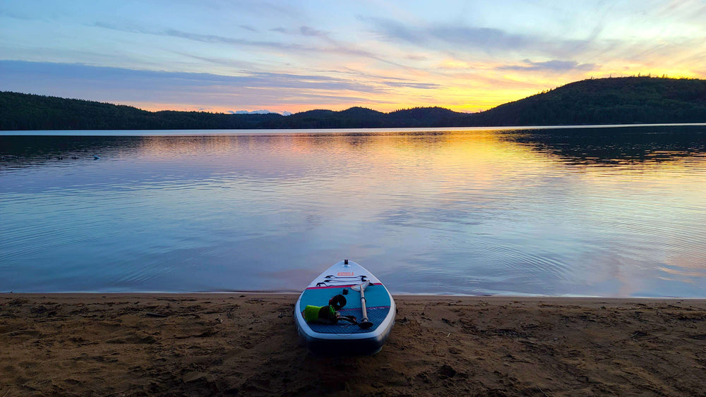 picturesque views of a lake at sunset with Red inflatable paddle board on the shoreline