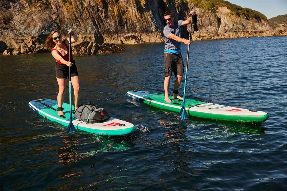 2 people paddleboarding in the ocean together, smiling