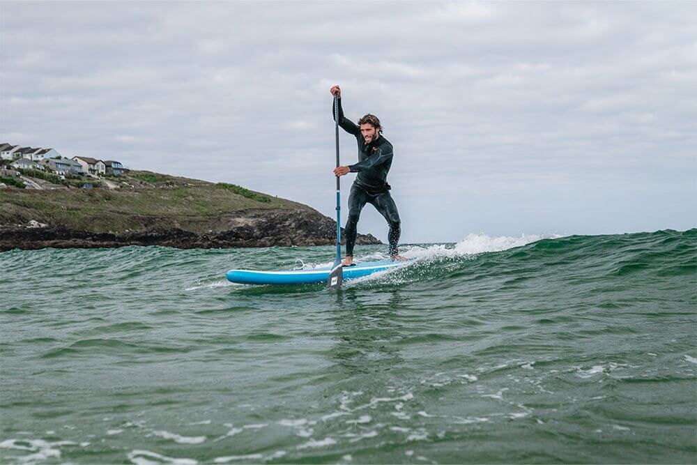 man paddling on a Whip MSL inflatable paddle board through the surf 