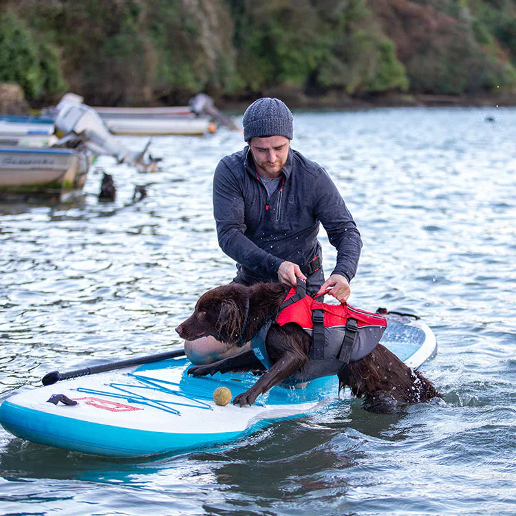 Man holding dog wearing Red Original dog buoyancy aid in red