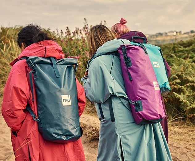 Three people carrying Red Original Waterproof Roll Top 10 Litre Dry Bags