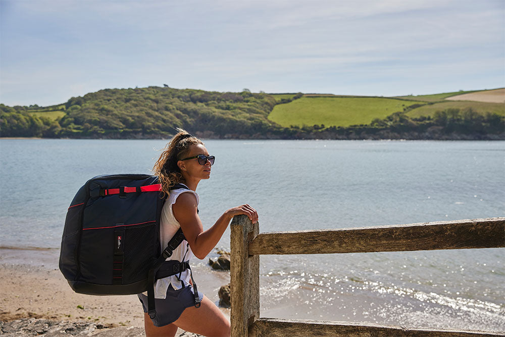 Woman on the beach carrying Red Original SUP Compact Backpack