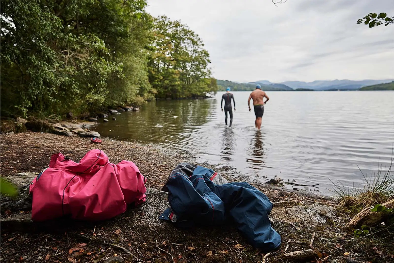 two people entering lake to swim