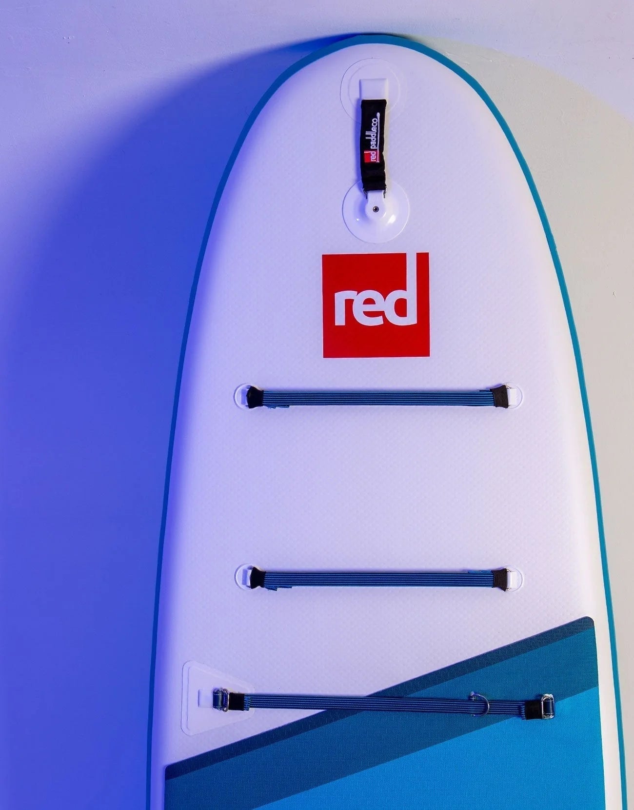 A paddleboard stood up against a wall with the Red logo on