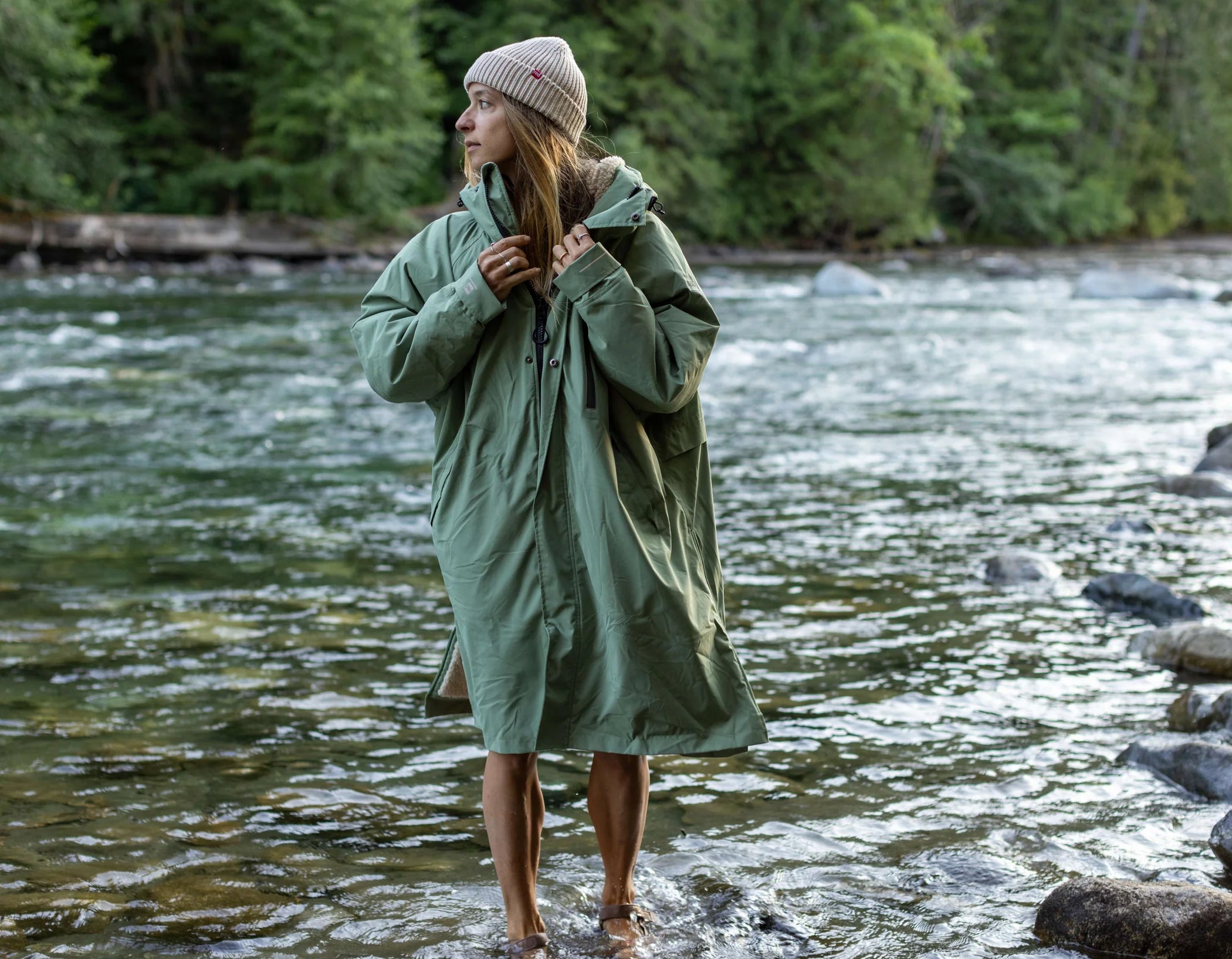 A woman wearing the long sleeve changing robe and flow beanie, paddling in the river